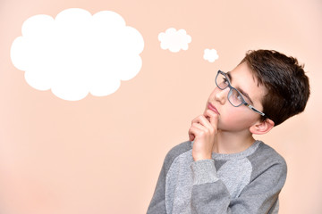 Thoughtful young boy wearing glasses with an empty thought bubble
