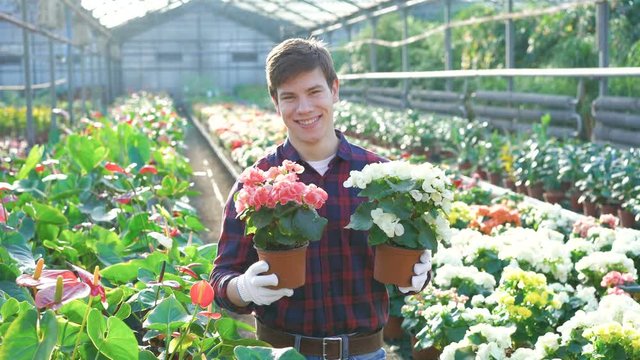 Happy gardener holding flowerpots and smiling 4K