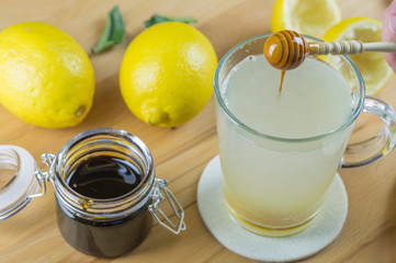 Ein Glas heiße Zitrone wird mit dunklem Honig gesüßt