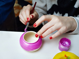 Fototapeta na wymiar Girl paints clay pot