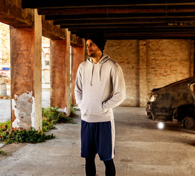 Young sports man standing in the old warehouse preparing for a run.