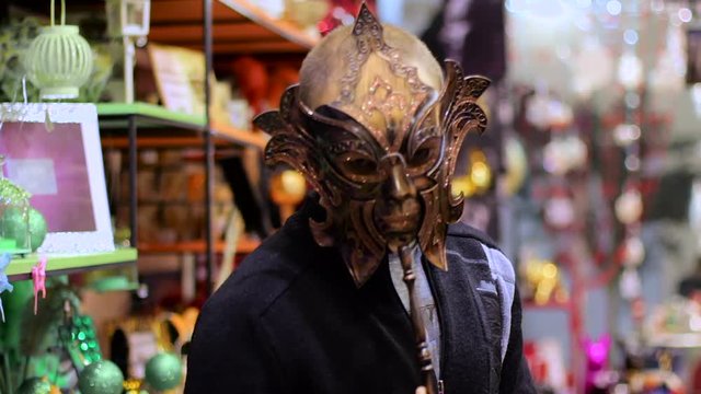 Cheerful young man wearing venetian masquerade carnival mask at store.