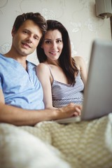 Happy couple using laptop on bed