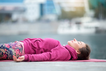Young attractive woman practicing yoga, lying in Dead Body exercise, Savasana, Corpse pose,...