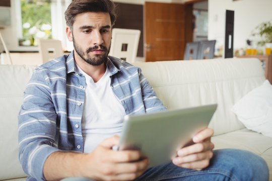 Man using digital tablet while relaxing on sofa