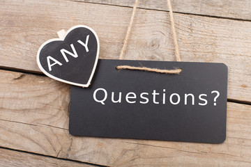 Blackboards with inscription "ANY Questions?" on wooden background