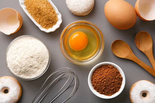 Baking ingredients flat lay (flour, egg, cocoa, sugar. spoons, cookies, whisker). Top view