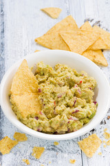 spicy avocado sauce in bowl and corn chips 
