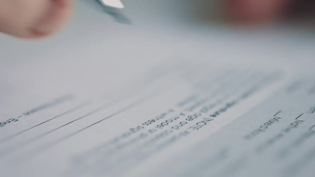 Side view of person heand signs the document. Close-up shot 