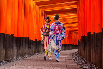 Naklejka premium Women in traditional japanese kimonos walking at Fushimi Inari Shrine in Kyoto, Japan