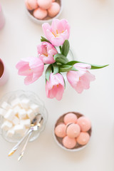 Fototapeta na wymiar Spring background. Sweets and tea on a table with pink tulips.