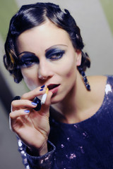 Obraz premium eine verrucht wirkendeFrau im 20er jähre Stil mit Wasserwelle raucht eine Zigarette