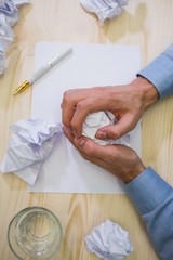 Close-up of graphic designer crumpling paper at his desk