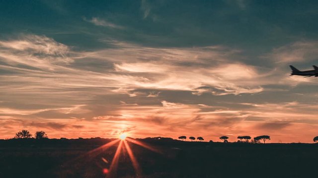 Vista laterale di un aereo passeggeri al decollo di fronte a un tramonto 