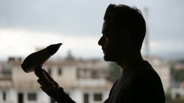 Cinemagraph. Silhouette of a man is drying his hair