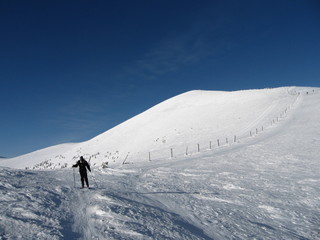 A skier on a long snow-covered road, in the mountains ski resort