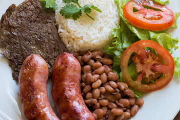 Photo with barbecue, calabresa, beans, rice, lettuce, tomato and coriander