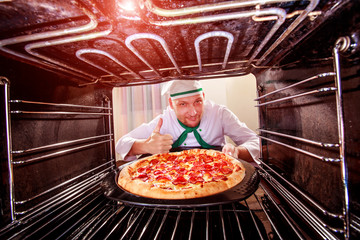 Chef cooking pizza in the oven.