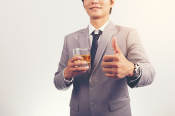 businessman holding a glass of whiskey and showing thumbs up.