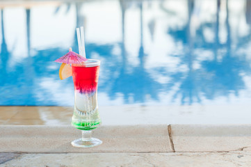 Colored cocktails on a background of water. Colorful cocktails near the pool. Beach party. Summer drinks. Exotic drinks. Glasses of cocktails on table near pool. Summer drinks photo concept. Сocktail