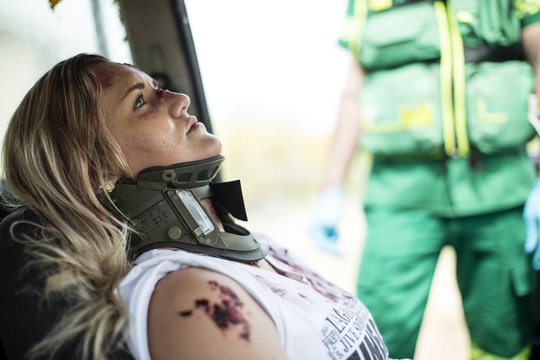 Car Crash Victim With Neck Brace Sitting Car With Paramedic In Background