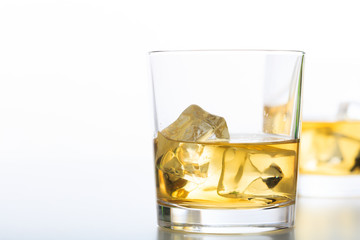 Glasses of whiskey and ice on white background