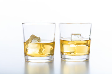 Glasses of whiskey and ice on white background