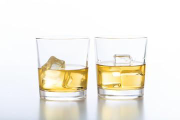 Glasses of whiskey and ice on white background