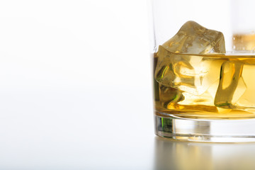 Glass of whiskey and ice on white background