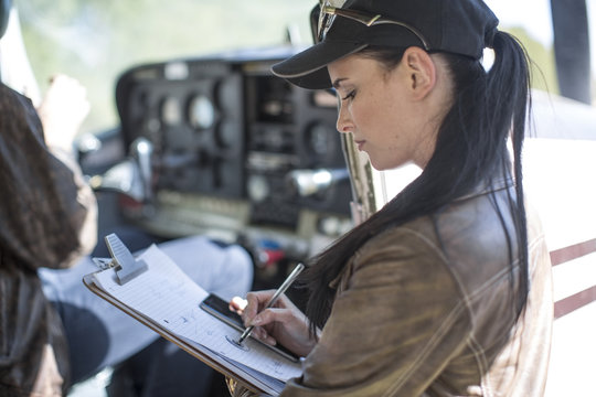 Female pilot inspecting light aircraft cockpit