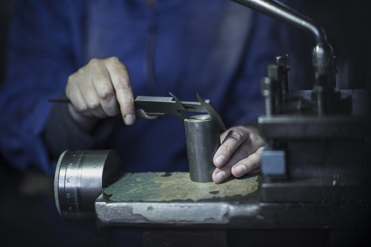 Woman using Vernier caliper in workshop to measure diameter