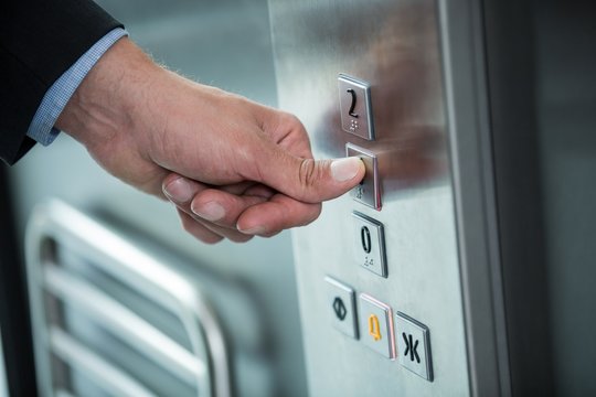 Hand of a businessman pressing the button in an elevator