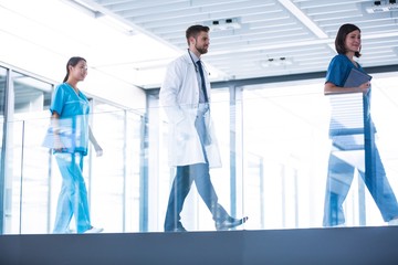 Doctor with nurses walking in corridor 