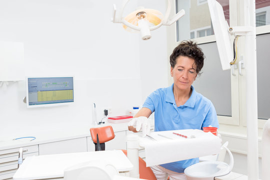 Zahnarzthelferin bereitet konzentriert den Behandlungsraum vor