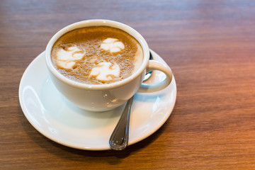 A cup of Latte art on wooden bar