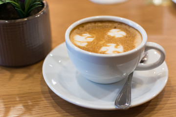 A cup of Latte art on wooden bar
