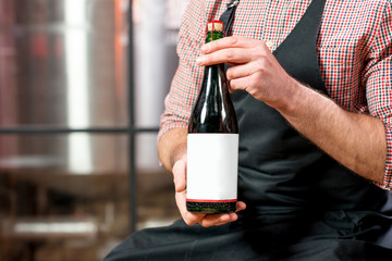 Close-up view on the beer or sparkle wine bottle in the male hands at the manufacturing
