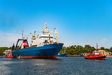 Tugboat towing fishing ship in port of Gdansk, Poland.