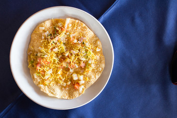 Indian food (Masala papad) on white dish with blue background