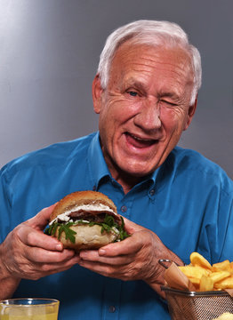 El abuelo feliz comiendo hamburguesa.