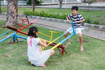 Brother and sister play seesaw.