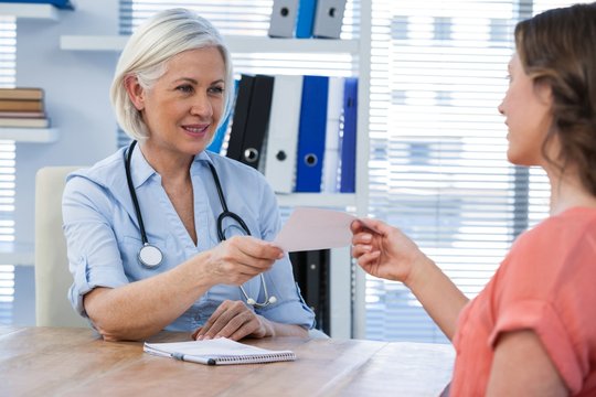 Doctor giving a prescription to her patient in medical office