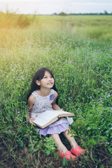 Cute asian girl Reading book at meadow in holiday