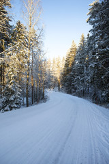 Obraz premium Curvy road on a winter day. Dangerous and slippery road during sunrise in Finland 