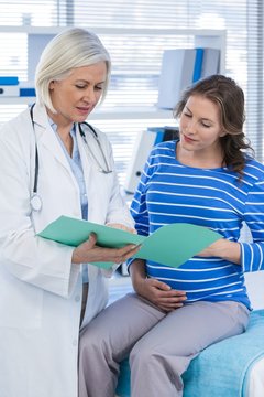 Doctor showing medical report to pregnant woman