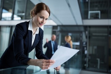 Businesswoman standing in corridor reading document in office