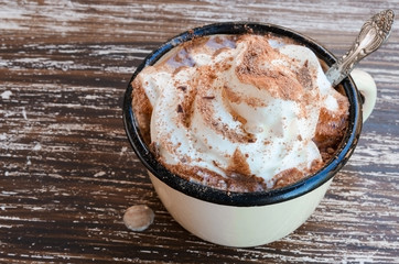 Close up of vintage mug of hot chocolate cocoa with whipped cream and chocolate crumbs  on wooden background. Top view. Winter times drink concept
