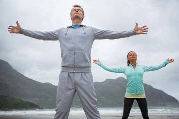 Couple standing with arms outstretched on beach