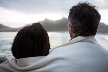 Rear view of couple wrapped in shawl on beach