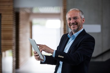 Naklejka na ściany i meble Cheerful businessman holding digital tablet